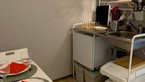 Uma cozinha compacta equipada com micro-ondas, pia e pequeno frigorífico.