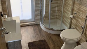 A modern bathroom with a glass shower enclosure, a toilet, and a sink.