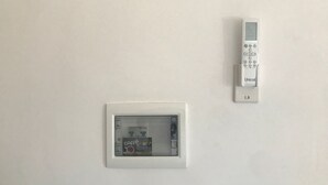 A wall-mounted thermostat and a window with a cafe store sign.