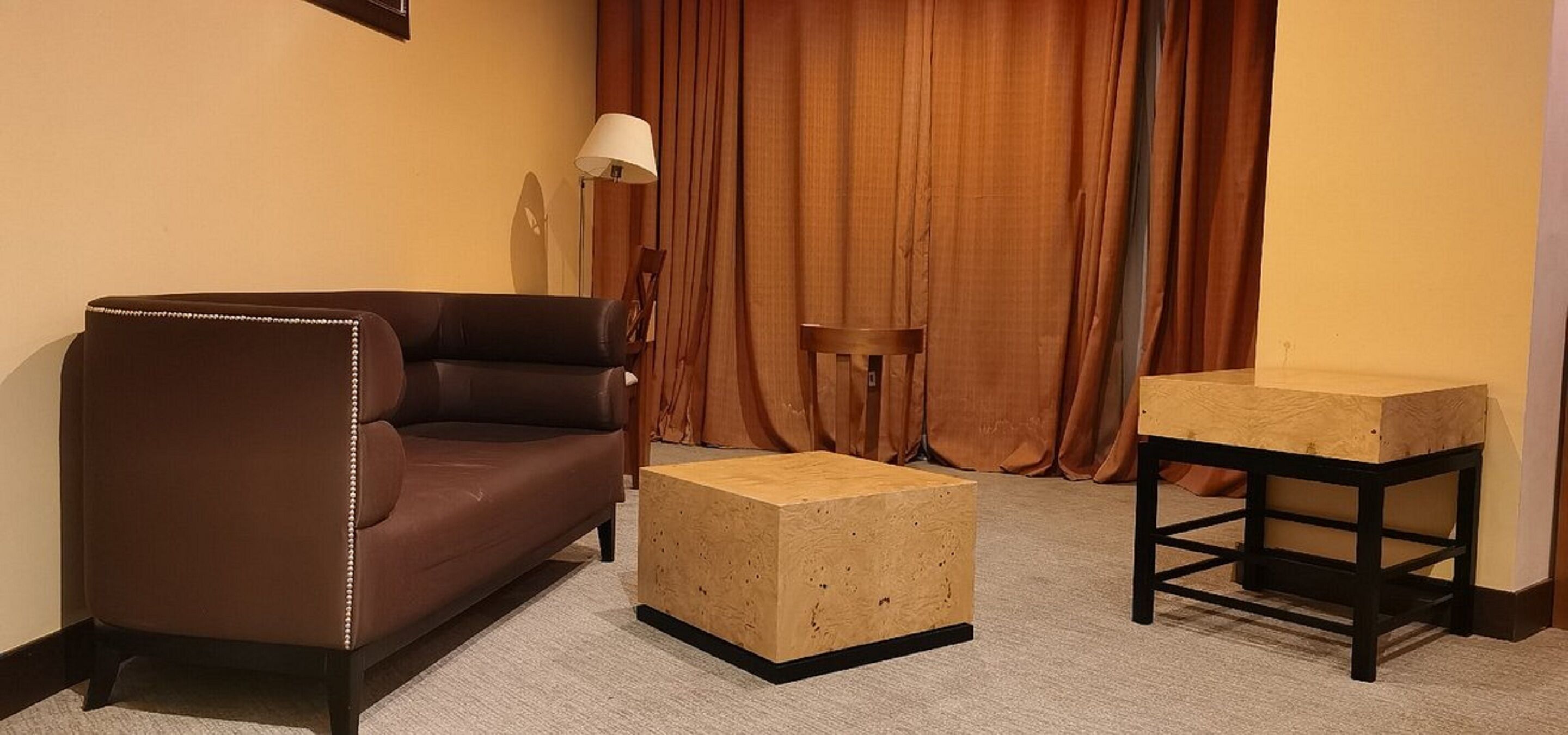 A room with a brown leather sofa, a wooden coffee table, and a small wooden side table.
