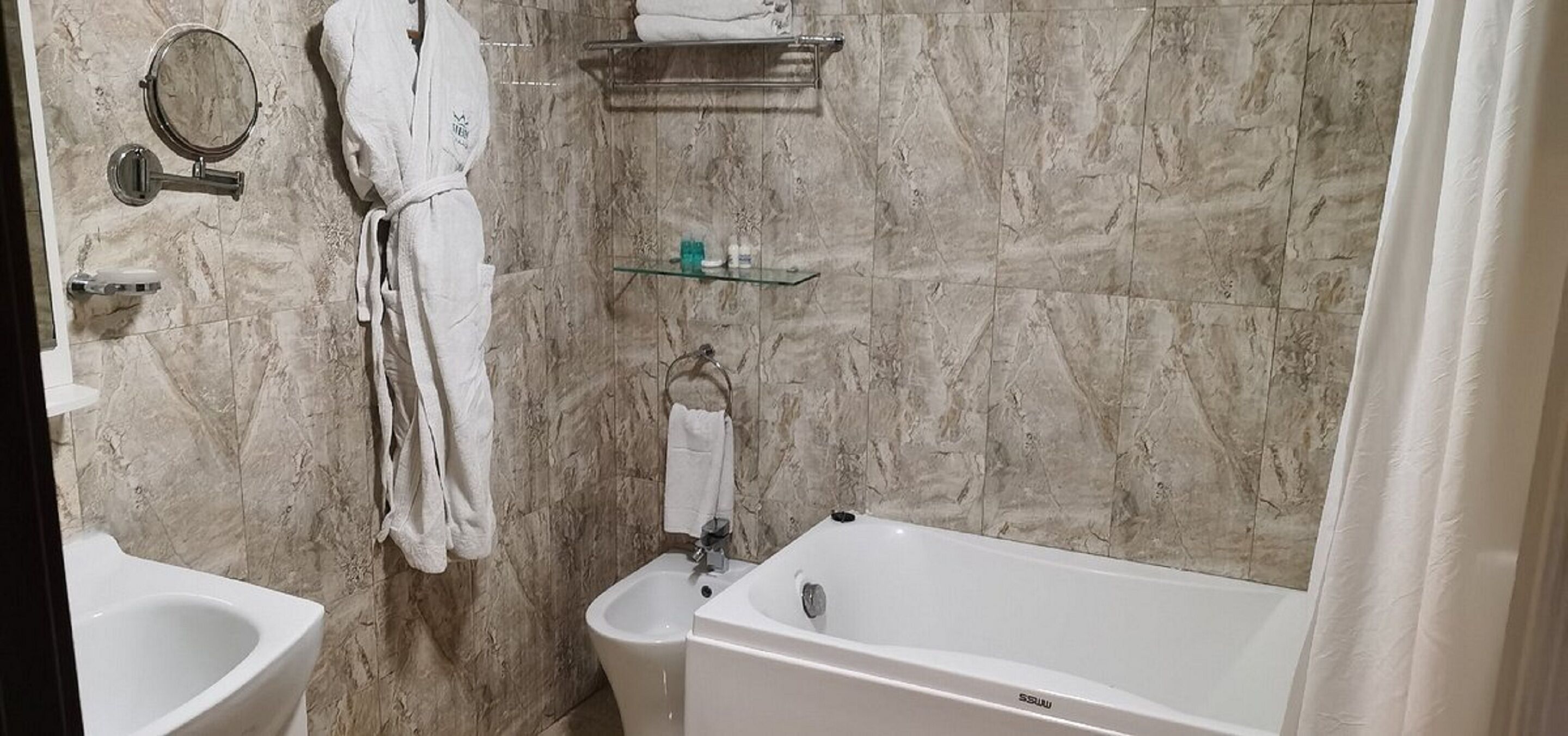 Une salle de bain équipée d’une baignoire, d’un bidet, d’un miroir et d’un porte-serviettes.