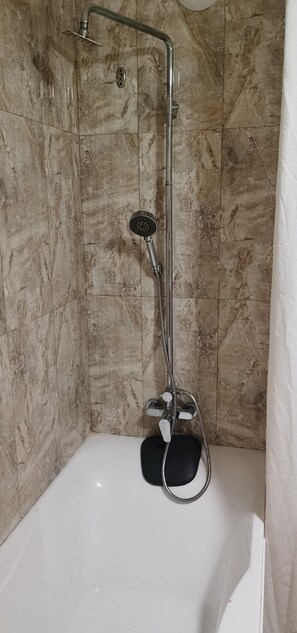 Ein Duschbereich mit Handbrause, Wandarmatur und Badewanne.