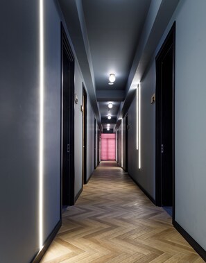 A long, narrow hallway with wooden flooring and modern lighting fixtures.