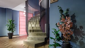 Un escalier avec une rampe en métal, un pot de fleurs et un panneau indiquant l’emplacement d’un café.