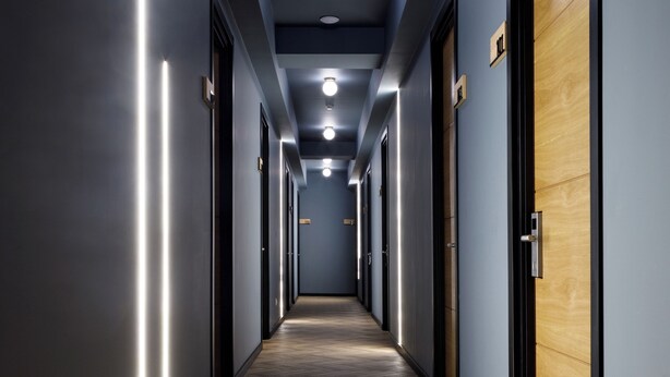 Un long couloir étroit, doté d’un plancher en bois et de murs peints dans une nuance de bleu foncé.