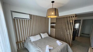 Una habitación de hotel con cama, lámpara colgante, armario empotrado y kitchenette.