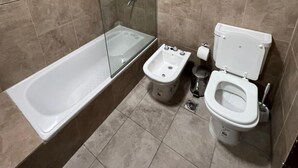 Un baño con bañera, bidé e inodoro.