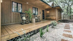 A wooden cabin with a porch, rocking chairs, and potted plants.