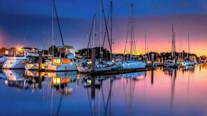 A marina at dusk with several sailboats docked.