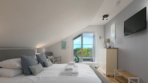 Une chambre à coucher avec un grand lit, une commode, un téléviseur et une fenêtre donnant sur l’extérieur.