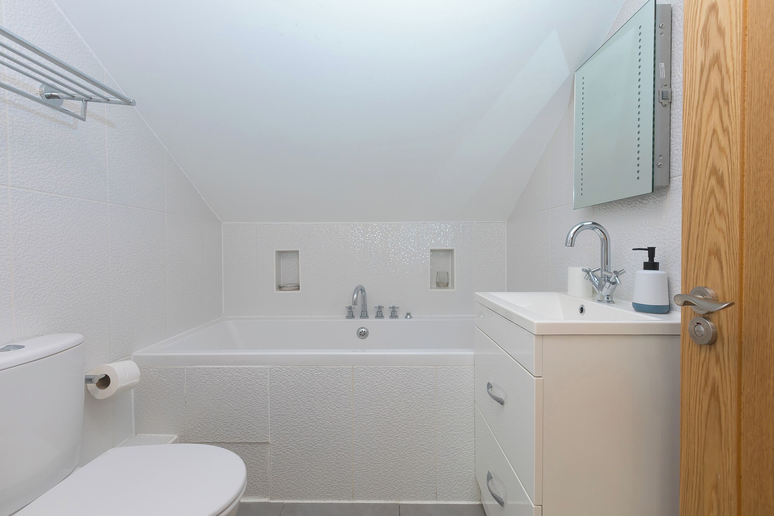 A small, modern bathroom with a toilet, bathtub, and sink.
