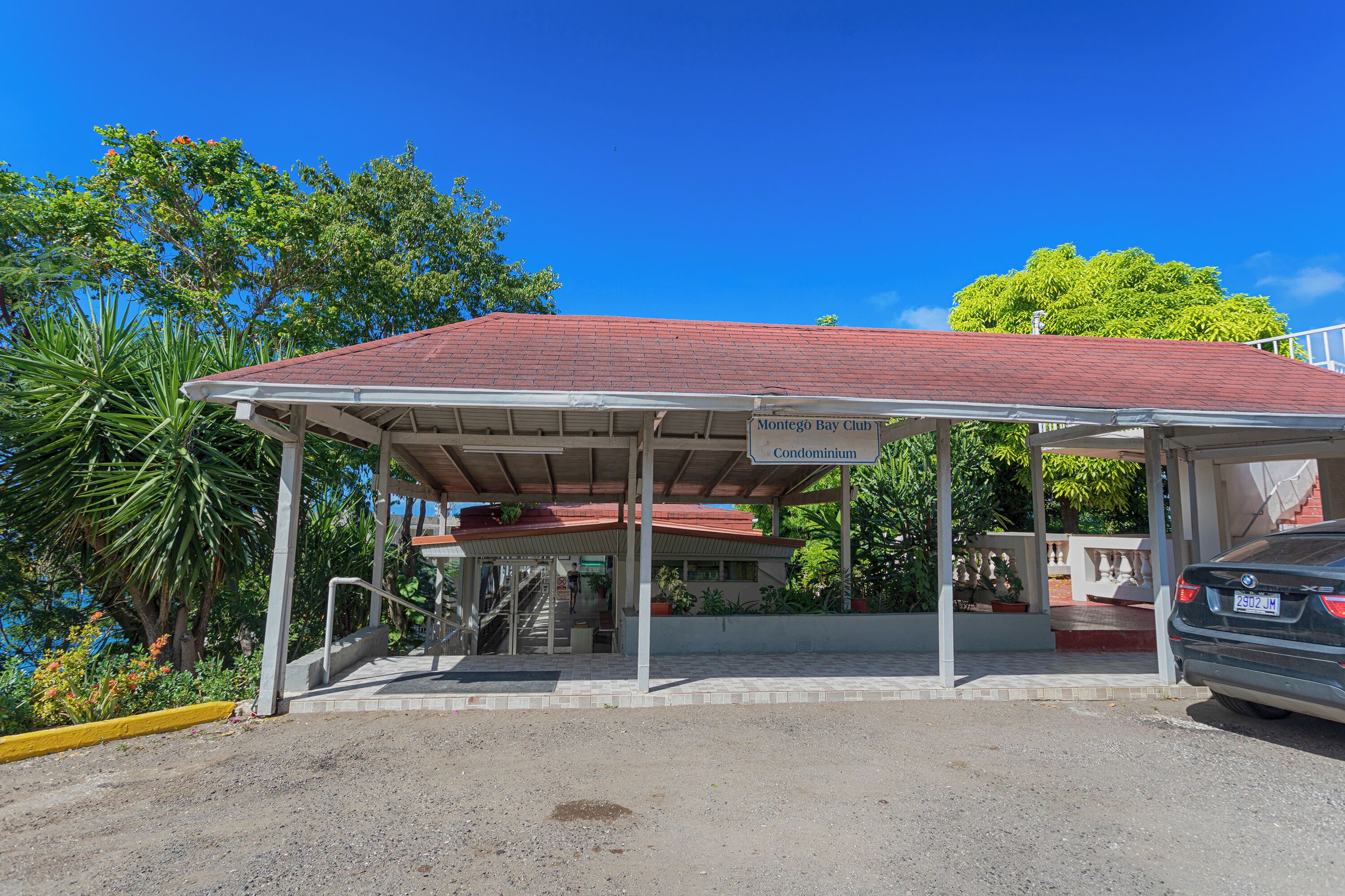 A covered parking area with a sign for 'Montego Bay Club Condominium.'