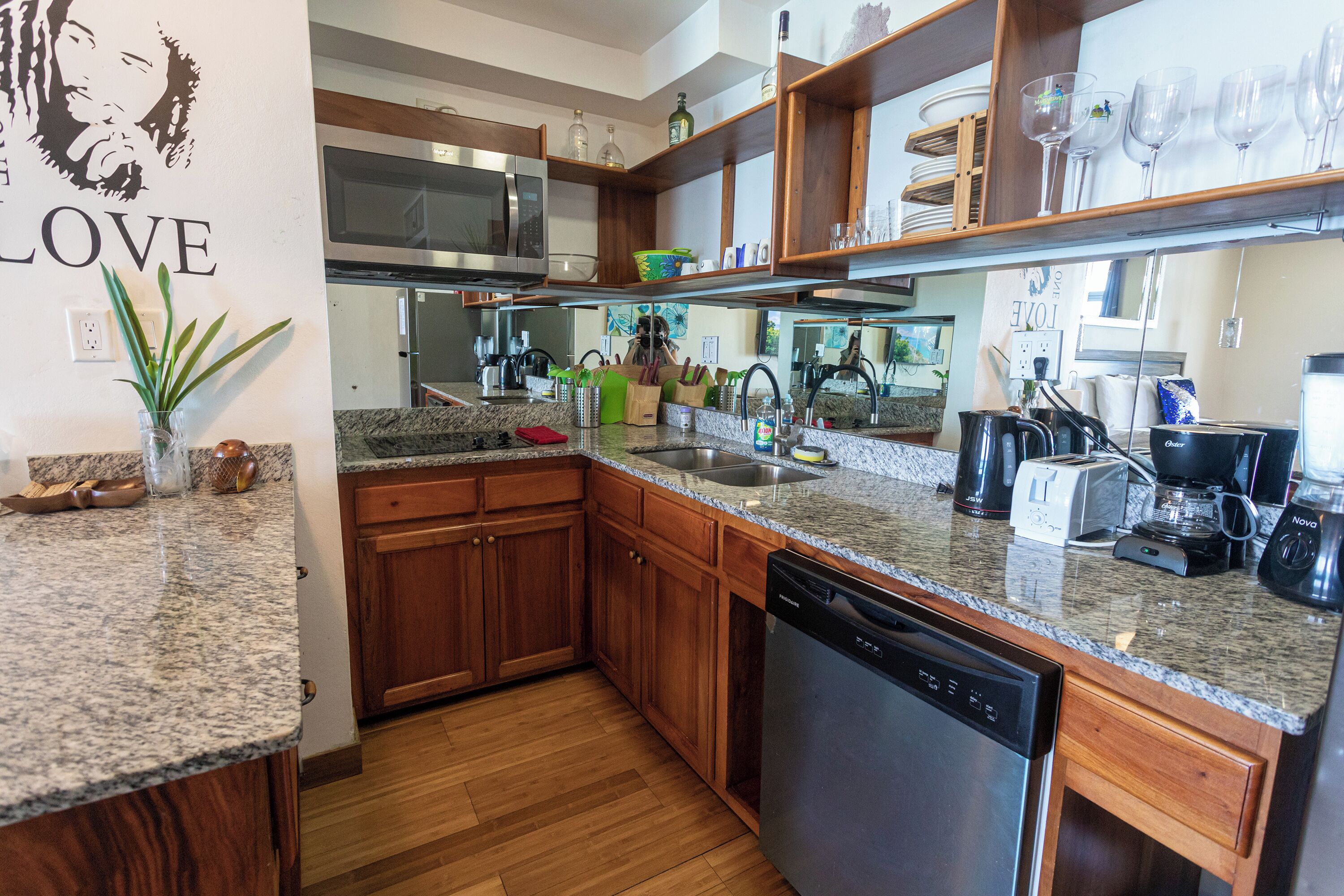 A modern kitchen with granite countertops, wooden cabinets, a dishwasher, a microwave, and a coffee maker.
