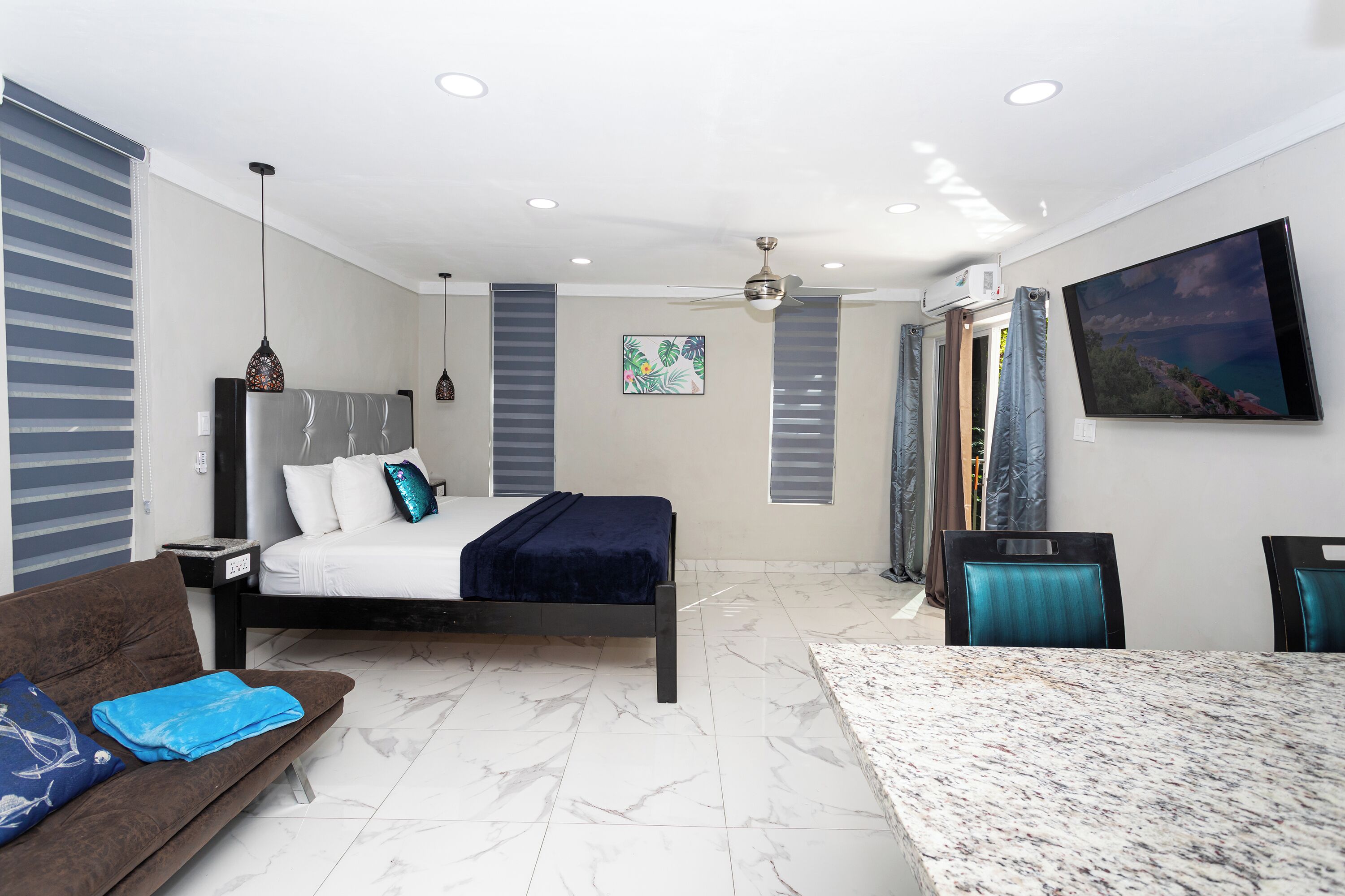 Une chambre moderne comprenant un lit, un canapé, une table à manger et un ventilateur de plafond.