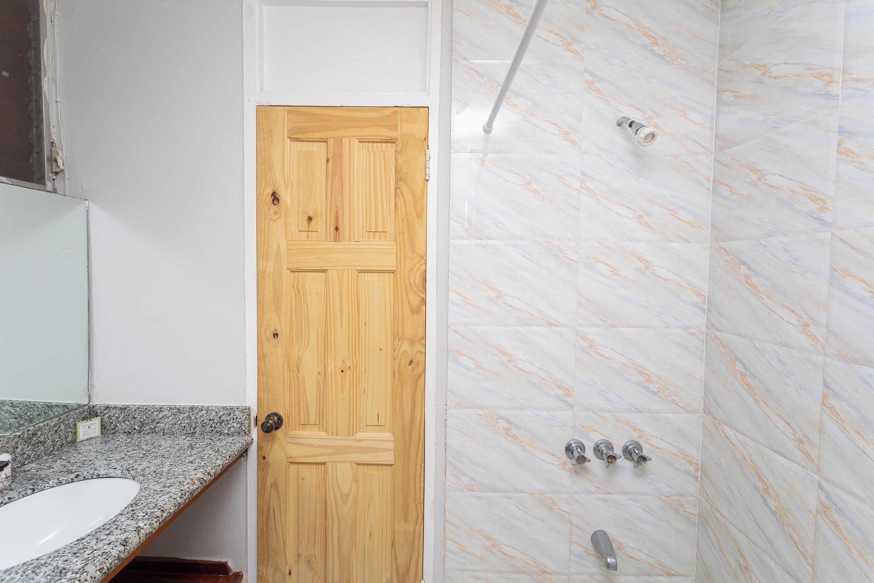 Un bagno con porta in legno, lavabo su piano in granito e pareti della doccia in marmo.