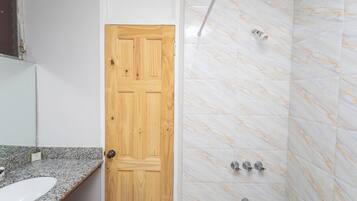 Un bagno con porta in legno, lavabo su piano in granito e pareti della doccia in marmo.