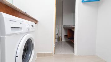 A laundry area with a white washing machine, a blue hanger, and a tiled floor.