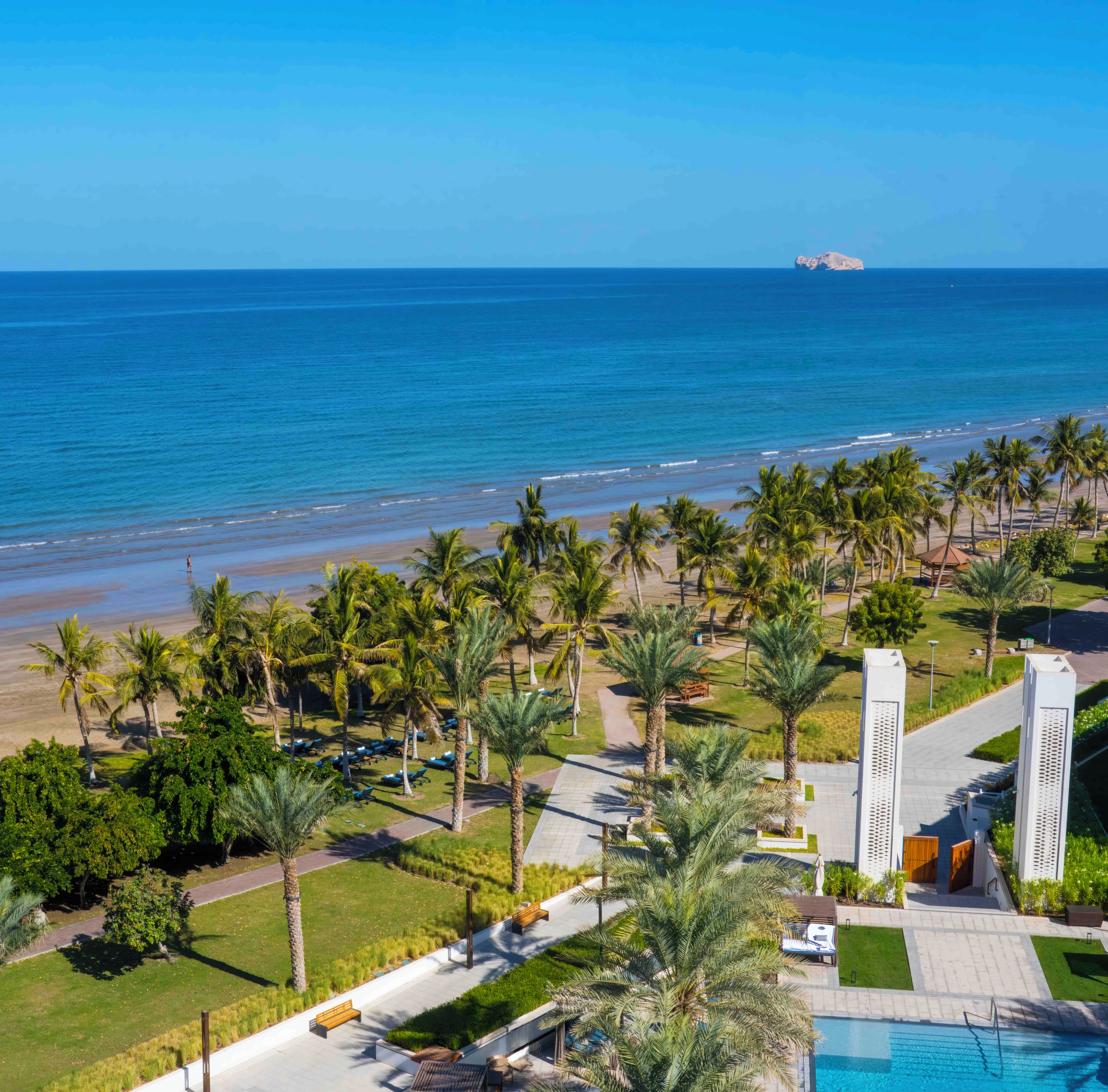 Un resort con piscina, palmeras y vista al océano.