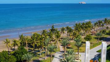 Un resort con piscina, palmeras y vista al océano.
