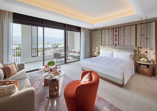 Une chambre d’hôtel moderne dotée d’un grand lit, d’un canapé, d’une table à manger et offrant une vue sur la ville grâce à de grandes fenêtres.