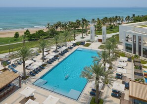 A pool with a view of the ocean, surrounded by palm trees and lounge chairs. - Mandarin Oriental Muscat (Muscat)