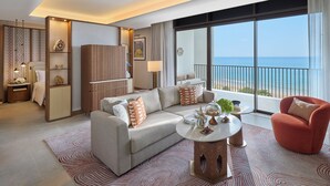 Une chambre d’hôtel moderne avec un canapé, un fauteuil et une table basse ronde.