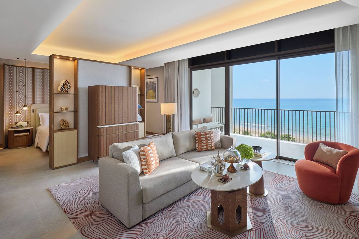 Una habitación de hotel moderna con sofá, sillón y una mesita redonda.