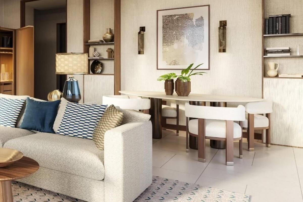Una sala de estar moderna con un sofá, una mesa de comedor y sillas. Hay una estantería, una lámpara y una obra de arte enmarcada en la pared.