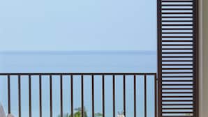 Ein Balkon mit Meerblick, ein Tisch mit einem Getränk und zwei Stühle.