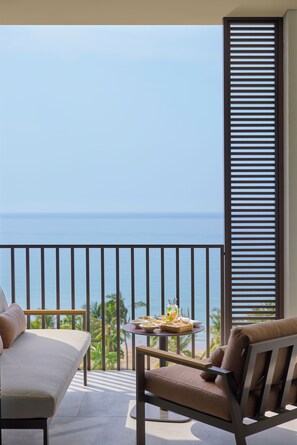 A balcony with a view of the ocean, a table with a drink, and two chairs. - Mandarin Oriental Muscat (Muscat)