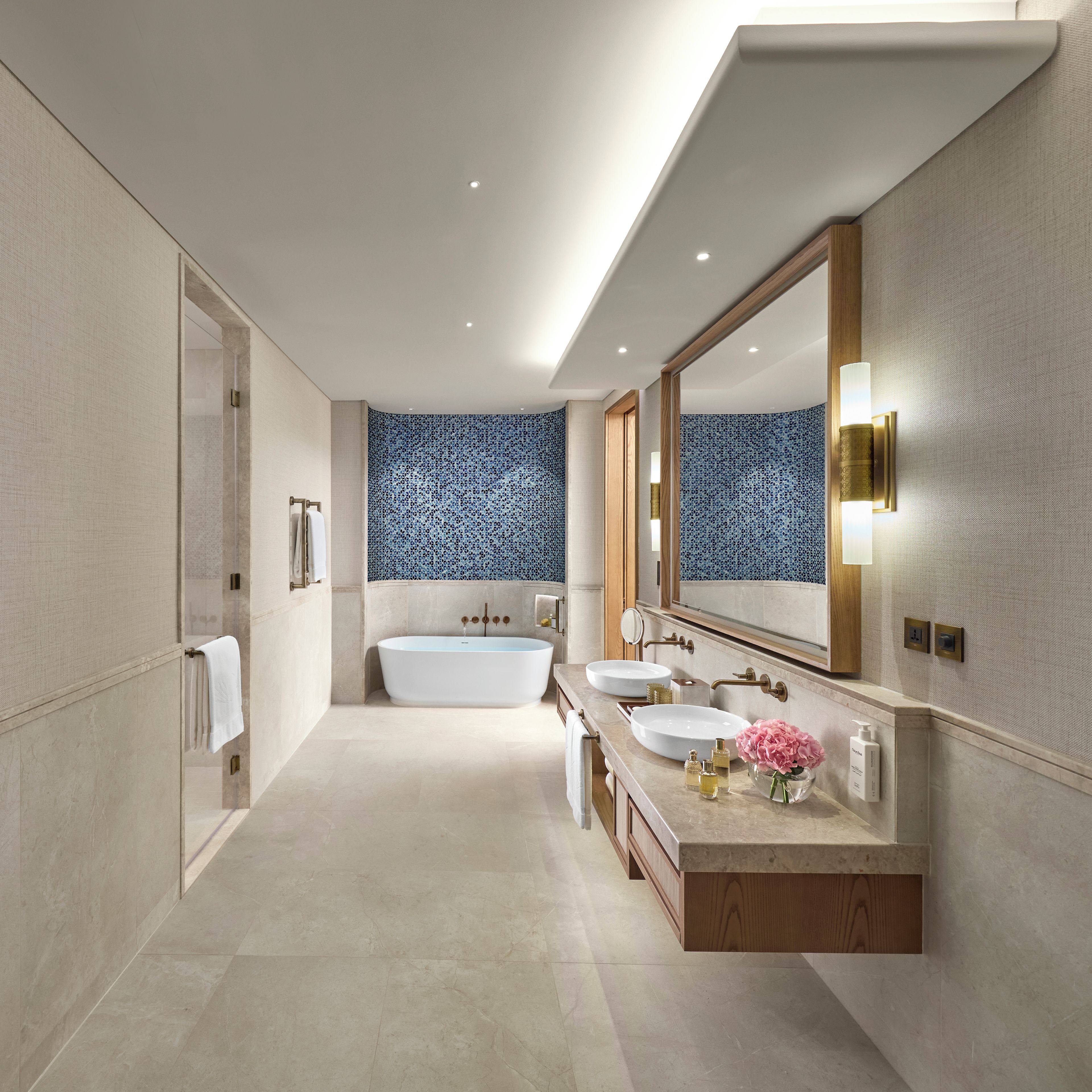 Un baño moderno con una bañera independiente, dos lavamanos y un espejo grande.