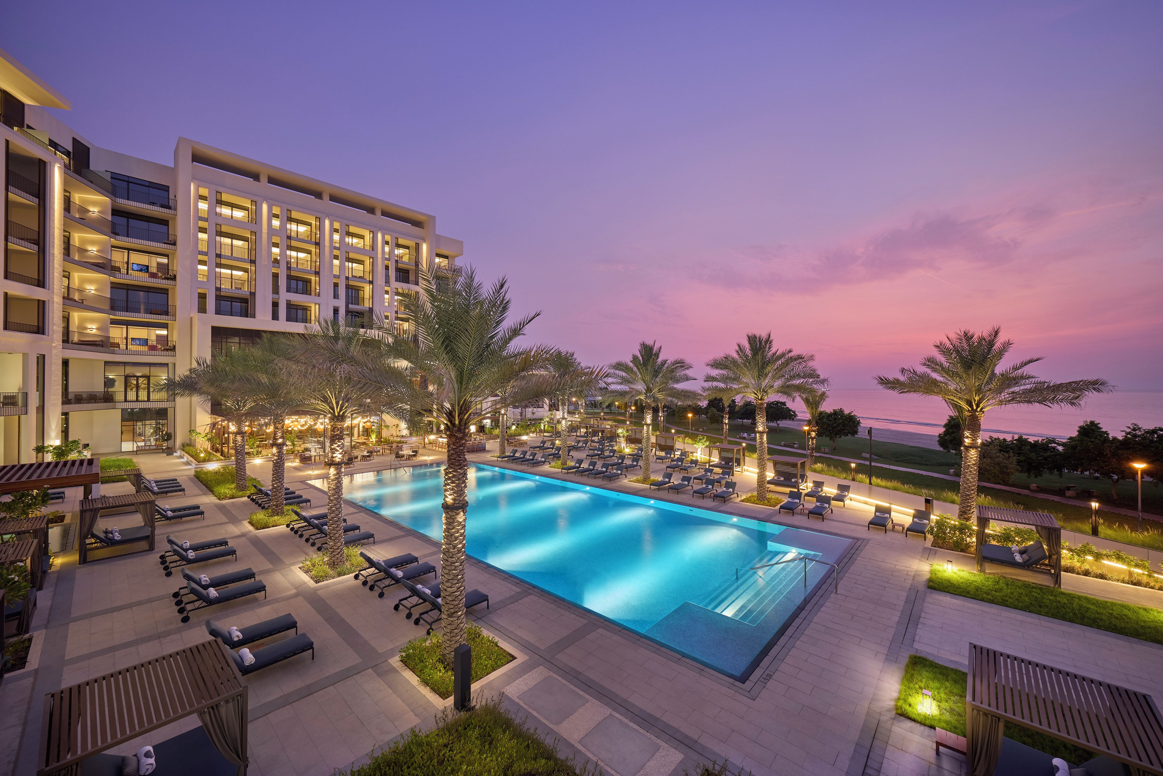 Un hotel con piscina, tumbonas y palmeras.