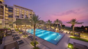 Un hôtel doté d’une piscine, de chaises longues et de palmiers.