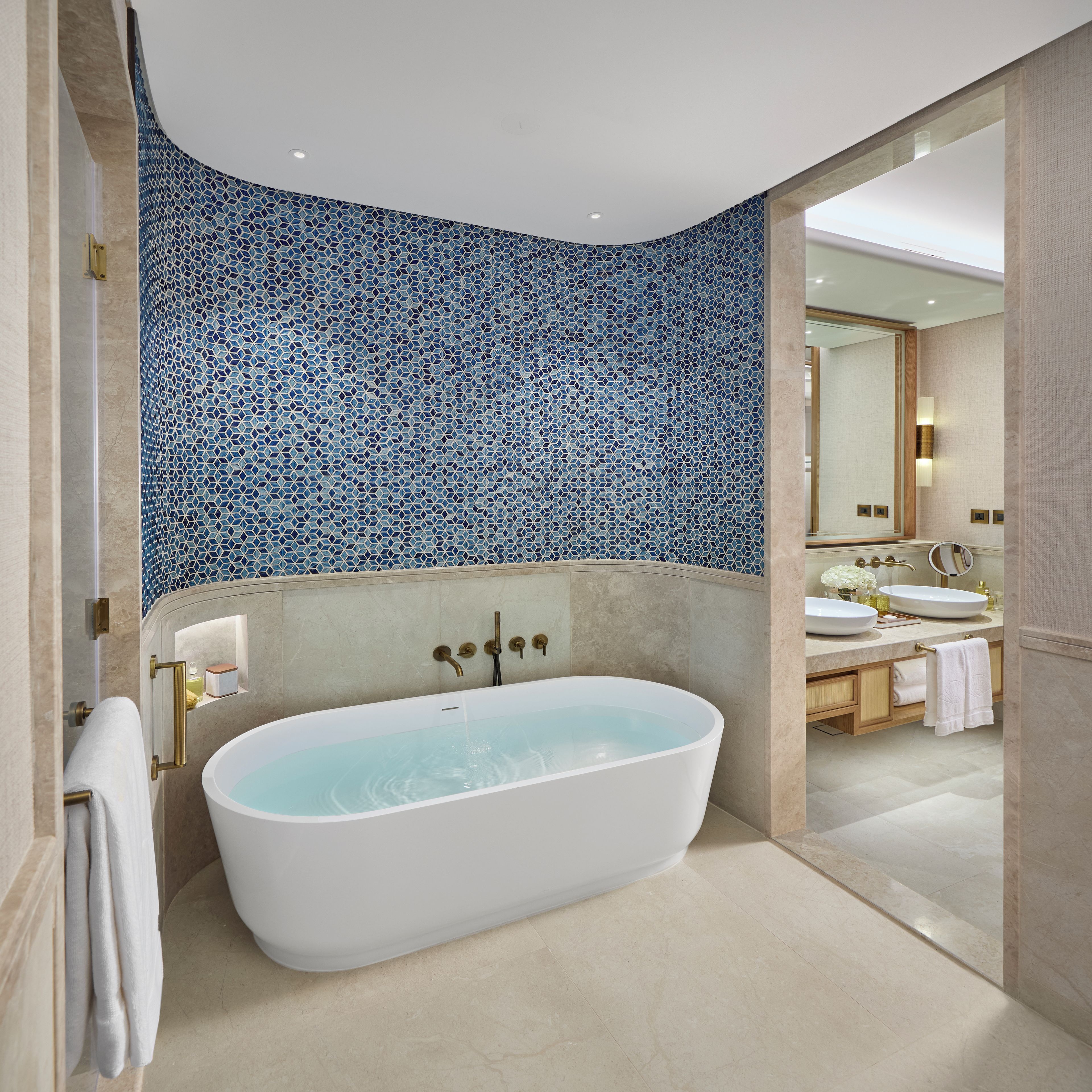 Un baño moderno con una bañera independiente, un espejo grande y una pared con azulejos.