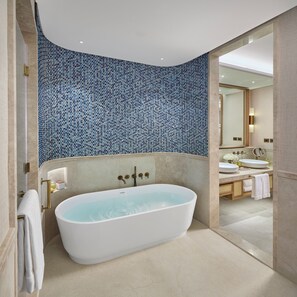 A modern bathroom with a freestanding bathtub, a large mirror, and a tiled wall. - Mandarin Oriental Muscat (Muscat)