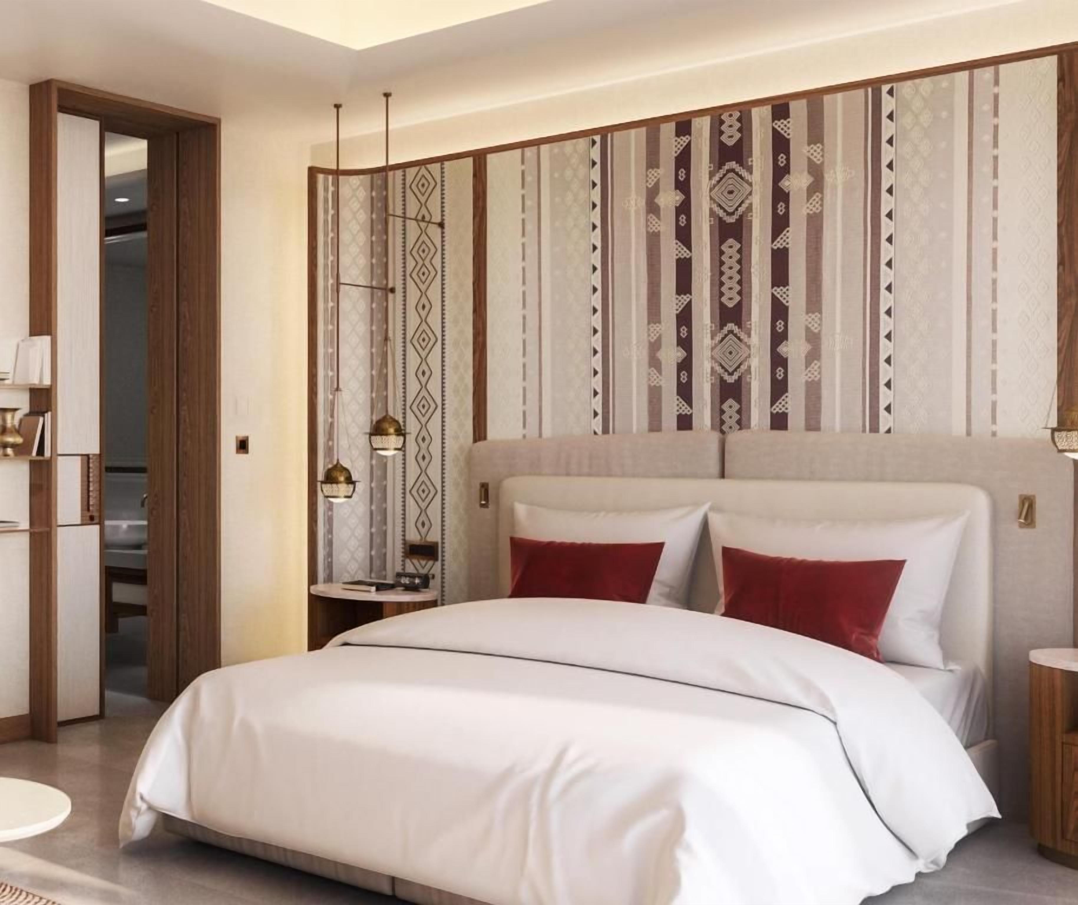 A modern hotel room with a large bed, a bedside table, a mirror, and a patterned wall.