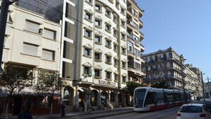 Een hotel met meerdere verdiepingen, in klassieke architectuur uitgevoerd, met boogvensters en balkons.