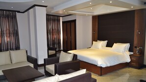 Een moderne hotelkamer met een groot bed, een slaapbank, een salontafel en een nachtkastje.