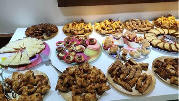 Une table de buffet proposant divers plats, notamment des pâtisseries, des viandes et des desserts.