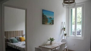 A room with a bed, a dining table with chairs, a potted plant, and a painting on the wall. - 10 mn à Pieds Vélodrome - T2 Marseille 09 (Marseille)