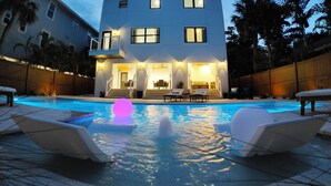 A modern two-story house with a swimming pool, outdoor seating, and a balcony. - Oceanview Beach Home, Private Heated Pool, 5 Star Amenities, Steps to Beach (Indian Rocks Beach)
