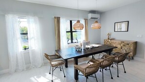 A dining area with a dark wooden table, wicker chairs, and two hanging wicker lamps. - Oceanview Beach Home, Private Heated Pool, 5 Star Amenities, Steps to Beach (Indian Rocks Beach)