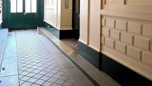 A hallway with a tiled floor, a green door, and a light fixture on the ceiling.