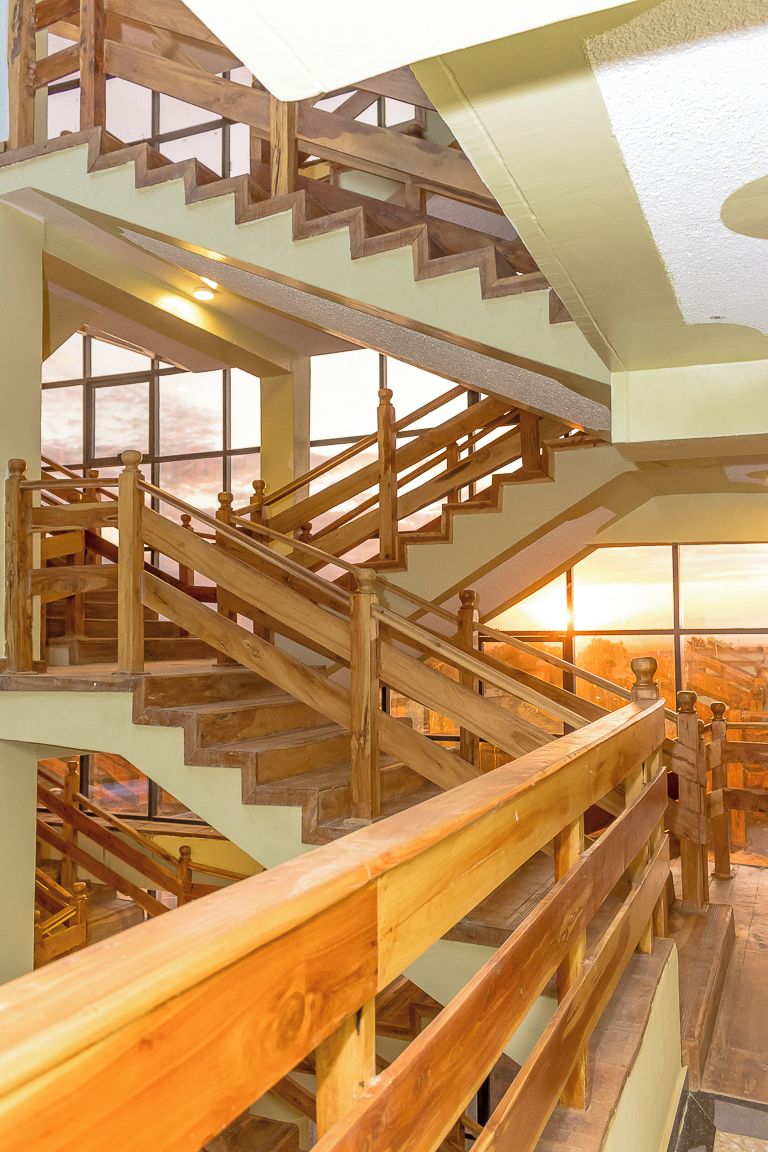 A multi-level wooden staircase with glass railings, leading to a room with a view.