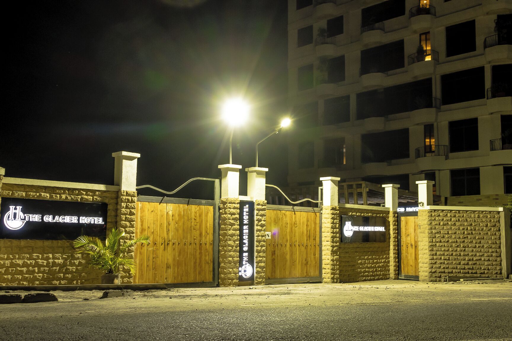 Una entrada cerrada con portón a Hotel Glacier, con una señal, un portón de madera y un muro de piedra.