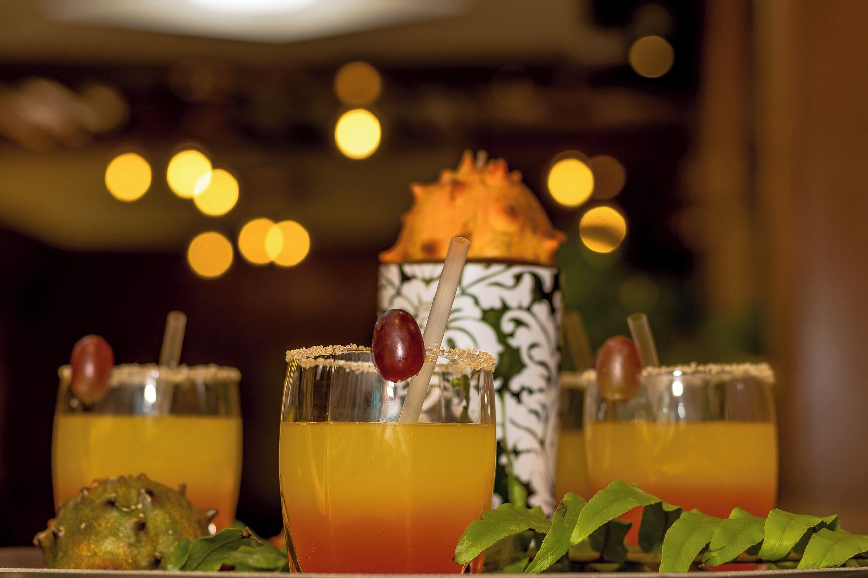 Trois cocktails décorés, un objet décoratif et un arrière-plan flou avec des lumières.