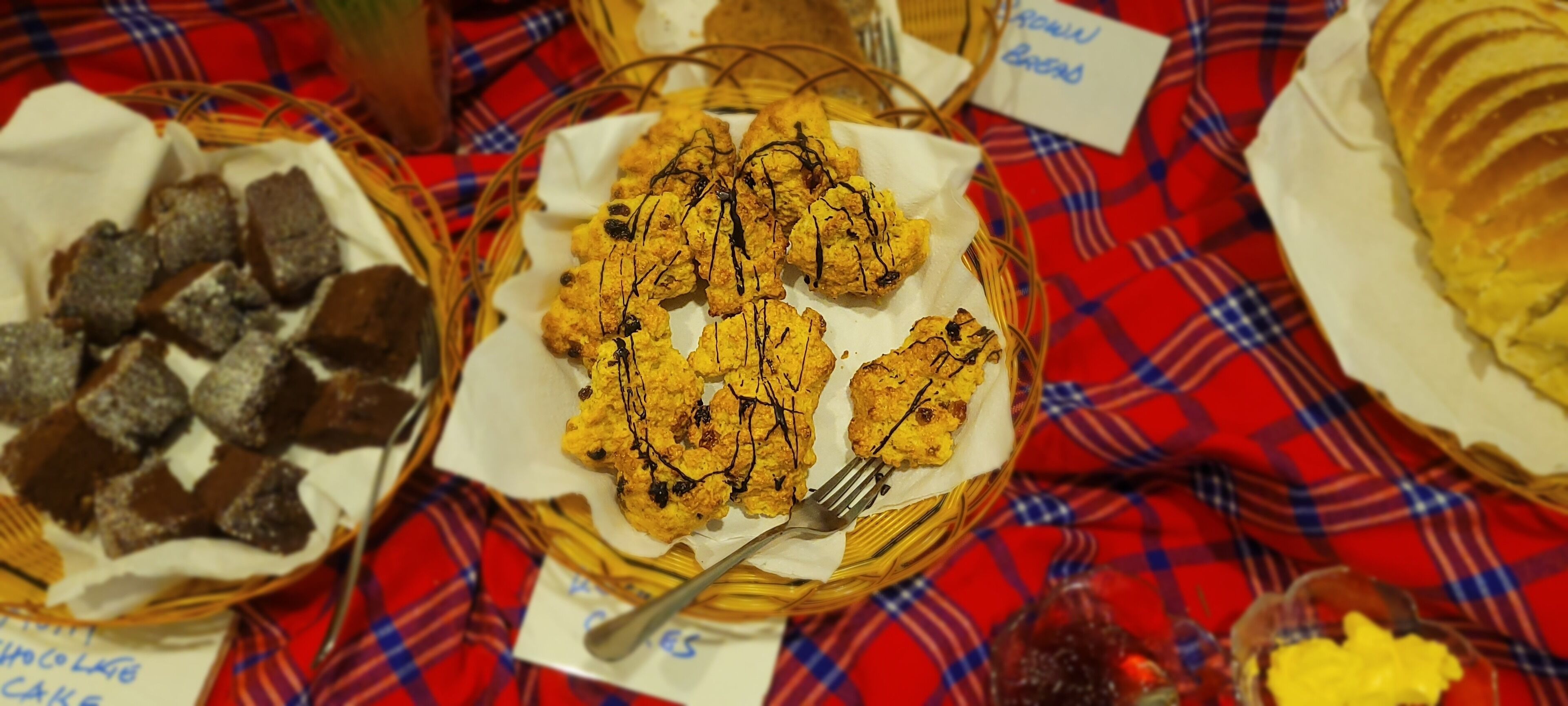 A table with various food items in baskets, including brownies and cookies, with labels indicating their names.
