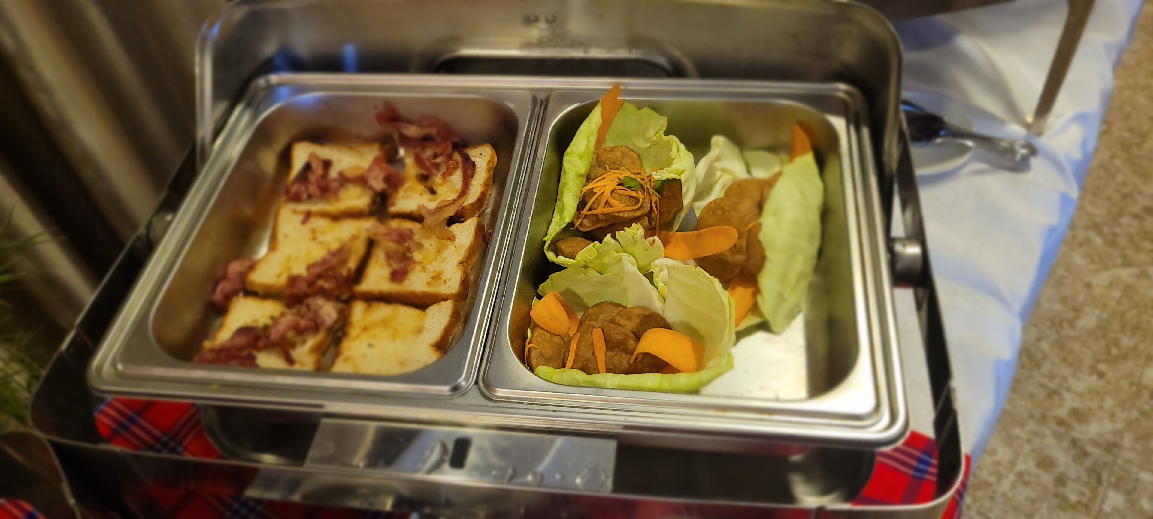 A buffet with two sections: one with toast and bacon, and another with meatballs in lettuce.
