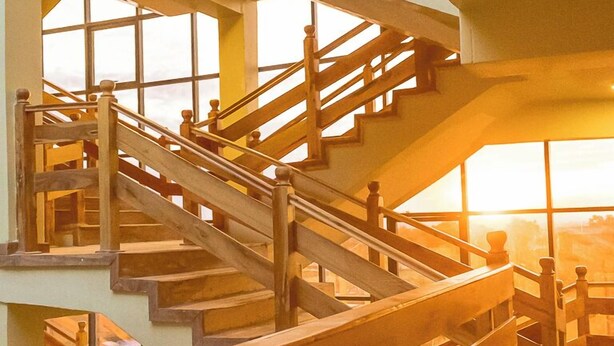 Una escalera de madera de varios niveles con vistas a la puesta de sol a través de amplias ventanas.