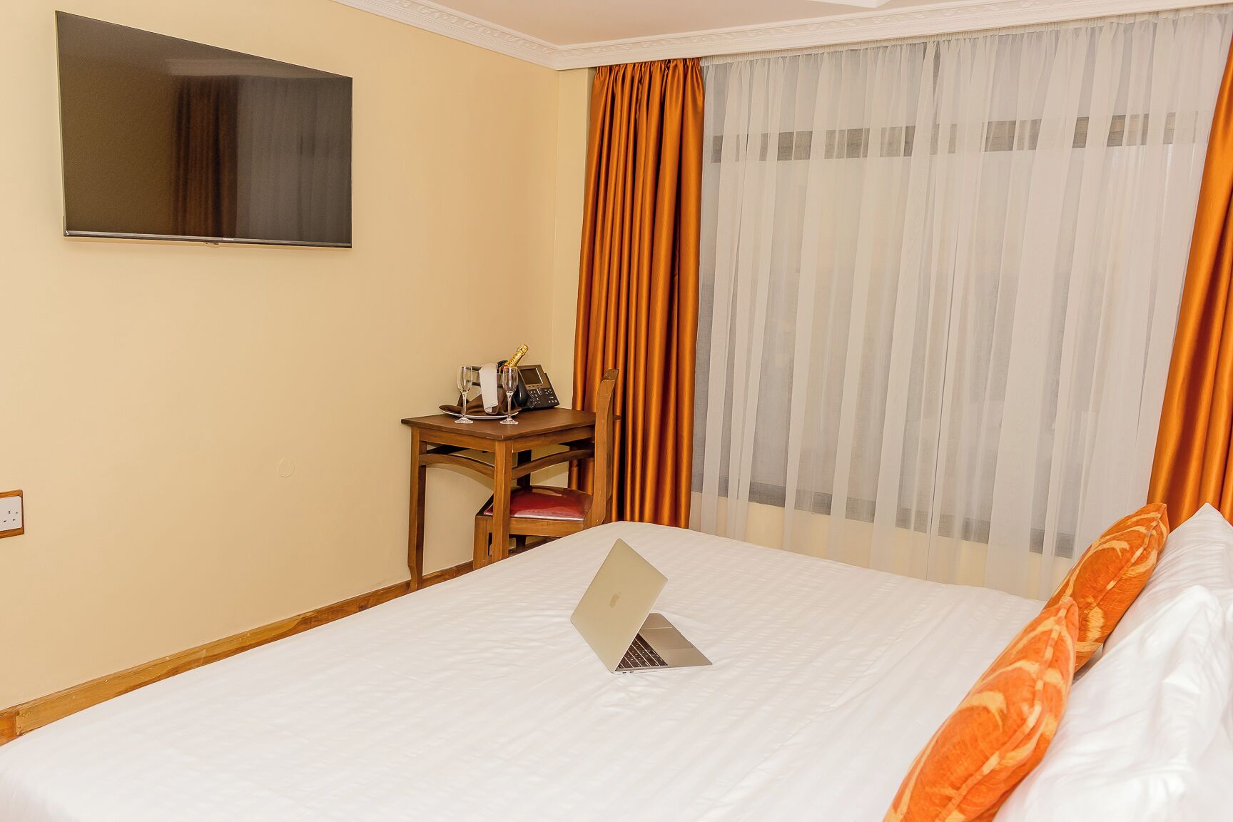 Una habitación de hotel con una cama, un escritorio con una computadora portátil, una silla y un minibar.